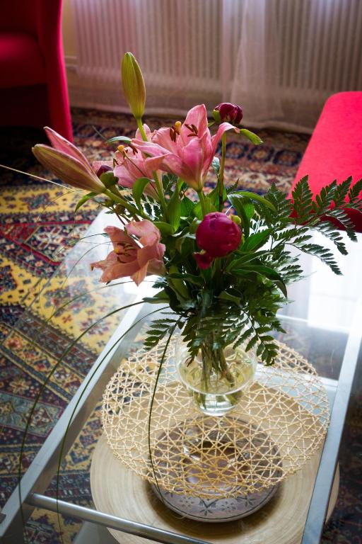 a vase filled with flowers on a glass table at Garden Apartment Donau-City (P&R) in Vienna
