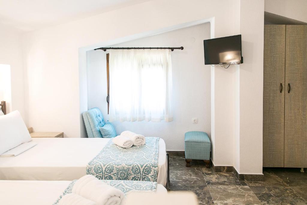 a hotel room with two beds and a tv at Alexandros Hotel Apartments in Vourvourou