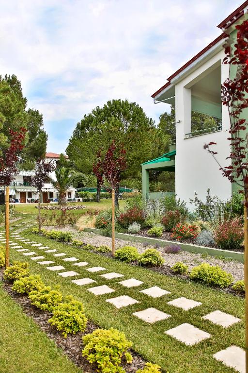 a garden with a stone path in front of a house at Alexandros Hotel Apartments in Vourvourou