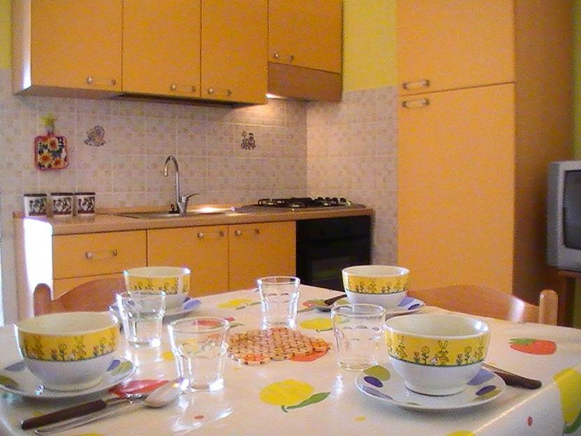 a kitchen with a table with bowls and glasses on it at Appartamenti Marilu in La Caletta