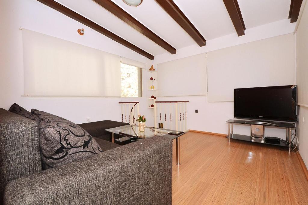 een woonkamer met een bank en een flatscreen-tv bij Apartment Irvin - sweet apartment in Trogir