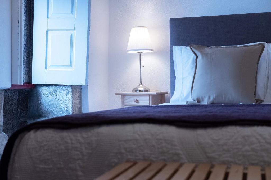 a bedroom with a bed and a lamp on a table at Portas da Villa in Miranda do Douro
