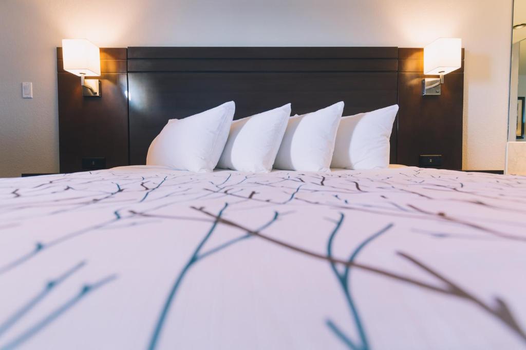 Cama en habitación de hotel con almohadas blancas en Service Plus Inns and Suites, en Grande Prairie