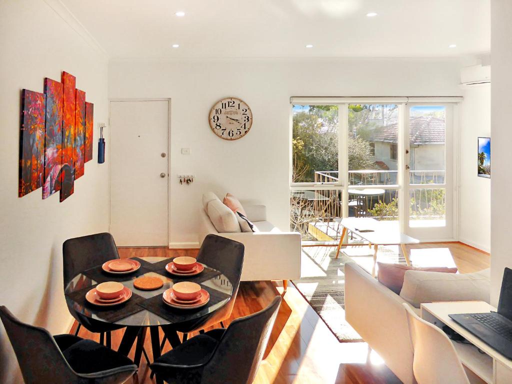 a living room with a table and chairs and a clock at Glen Iris, Quiet Boutique 2 bedroom Netflix, WIFI, Parking, Free Wine in Melbourne