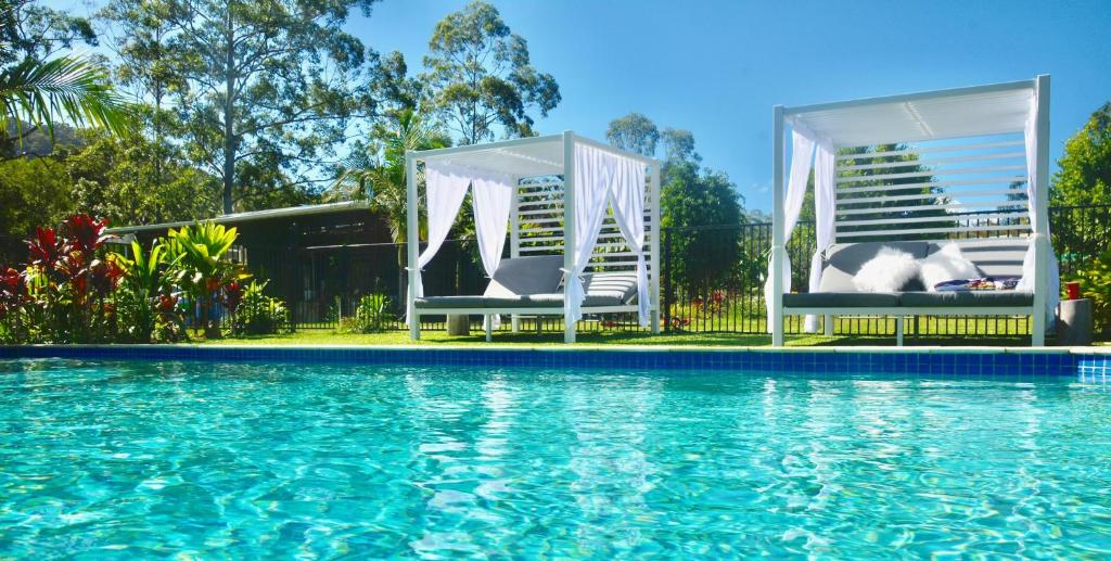 a swimming pool with two white chairs next to the water at La Rochér Eco Retreat in Stokers Siding