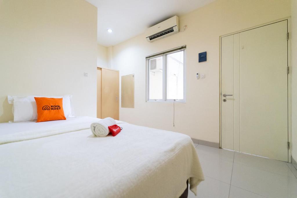 Una habitación blanca con una cama con un objeto rojo. en KoolKost near Ragunan Zoo - Minimum Stay 6 Days en Yakarta