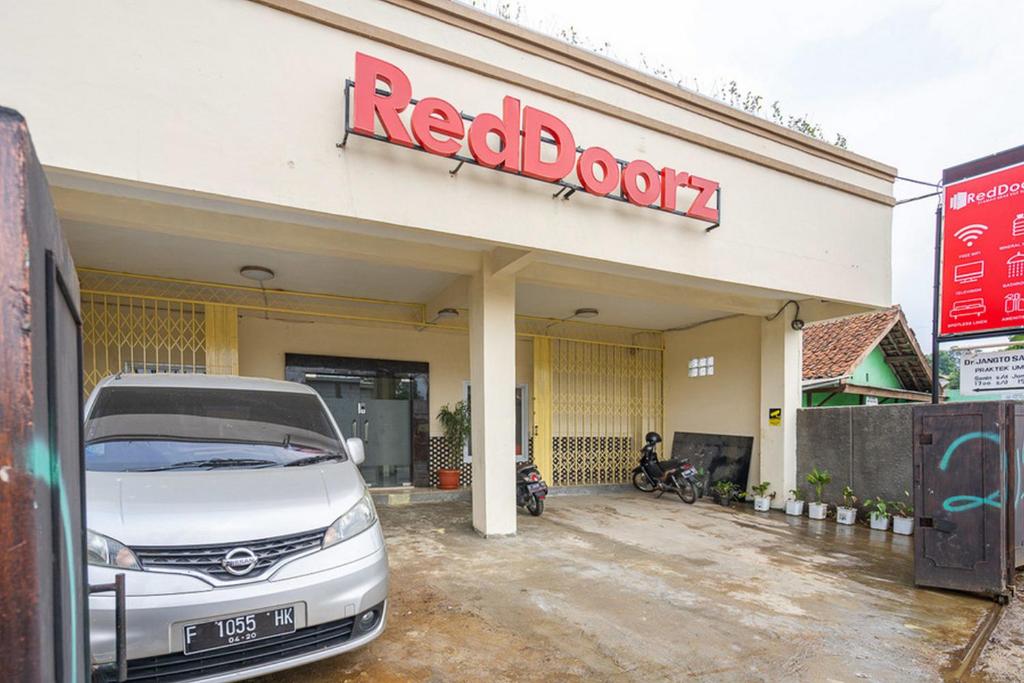 een witte auto geparkeerd voor een boekenwinkel bij RedDoorz Syariah near Exit Toll Ciawi in Bogor