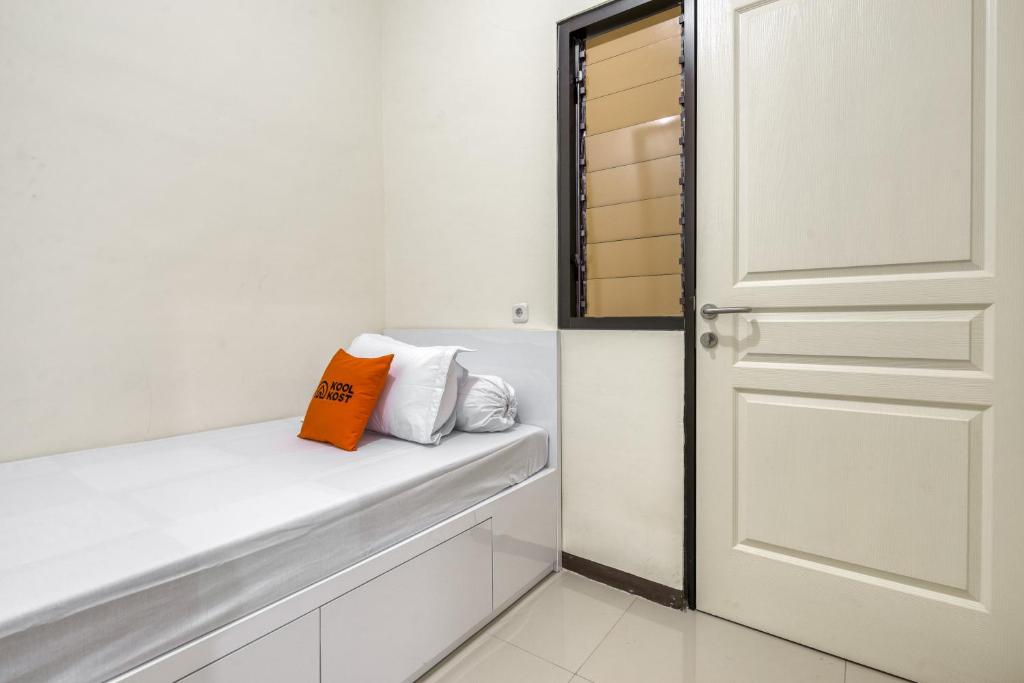 ein weißes Zimmer mit einer Tür und einigen Kissen in der Unterkunft KoolKost Syariah near Kaza Mall Surabaya in Surabaya