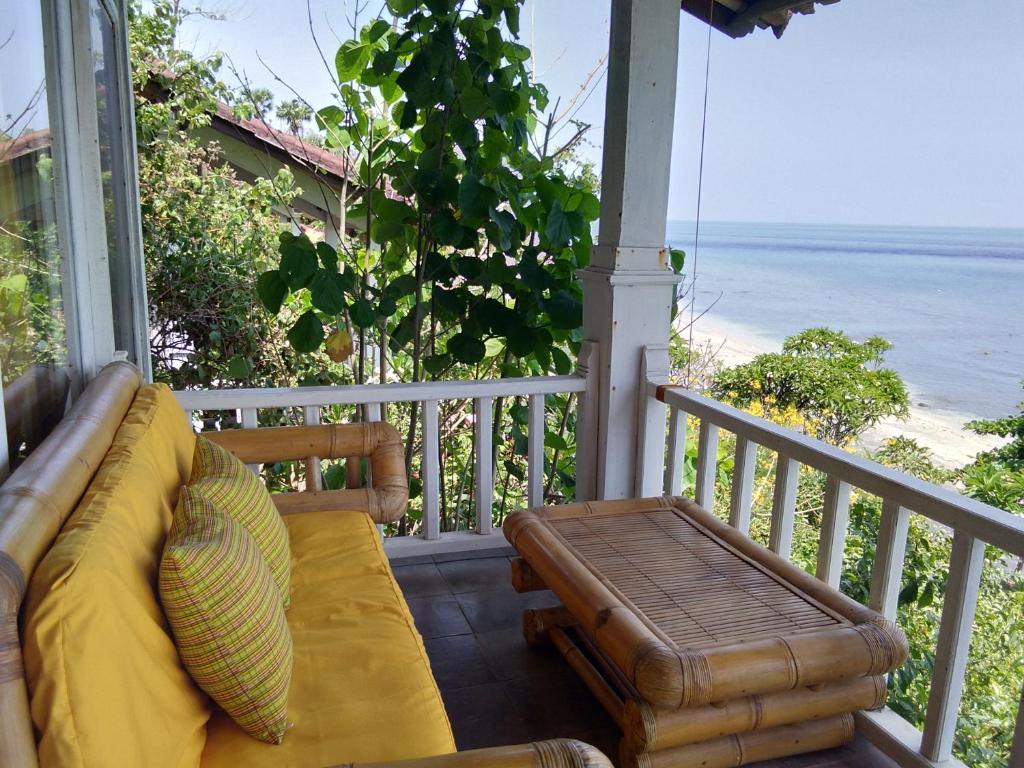 a couch on a porch with a view of the beach at Stairway To Heaven Bungalows and Restaurant in Amed