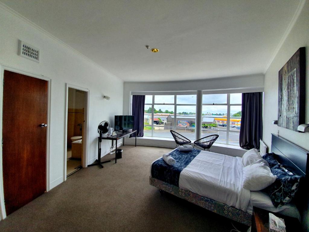 a bedroom with a bed and a large window at Putaruru Hotel in Putaruru