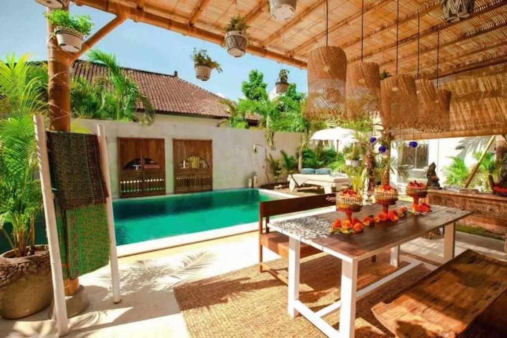 a patio with a table and a swimming pool at Villa Sarong 2 in Seminyak