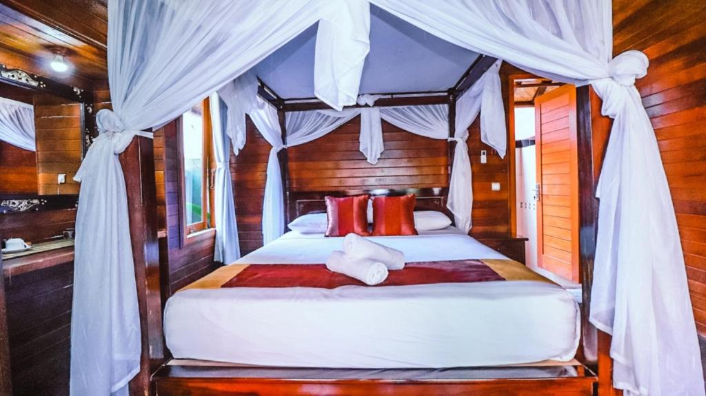 a bedroom with a canopy bed with red pillows at Pasih Kauh Villas in Nusa Lembongan