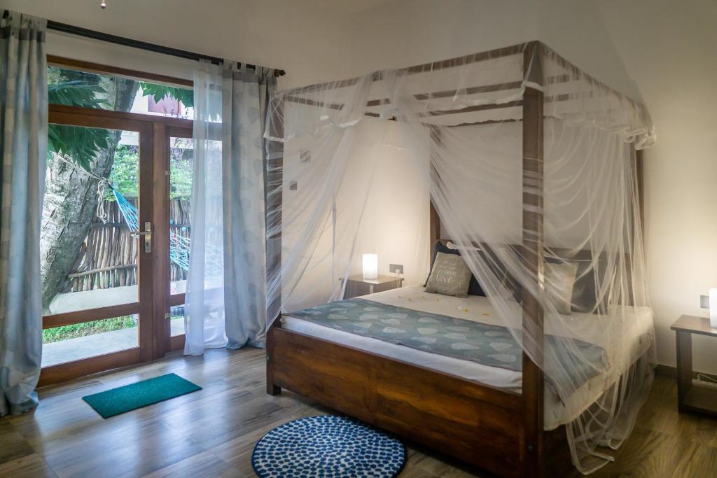a bedroom with a canopy bed and a large window at Madla rooms in Weligama