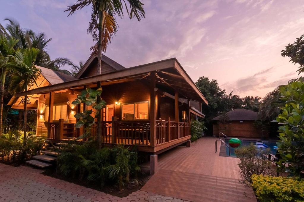 ein Haus mit einer Veranda und einem Resort in der Unterkunft Nature's Abode - The Wooden Villa at Morjim by StayVista in Morjim