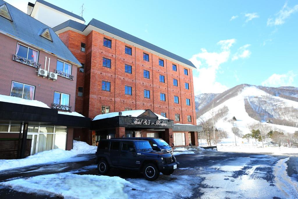 einen SUV, der vor einem Gebäude im Schnee geparkt ist in der Unterkunft Hotel Silk Inn Madarao in Iiyama