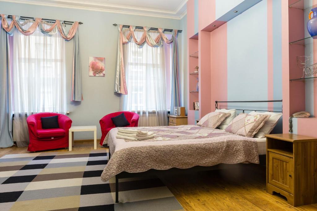 a bedroom with a bed and a red chair at Oksana's Apartments in Saint Petersburg