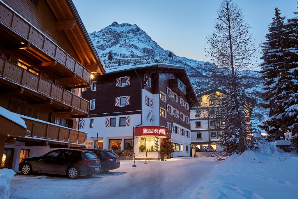 a hotel in the snow with a mountain in the background at Hotel Erzberg in Zürs am Arlberg
