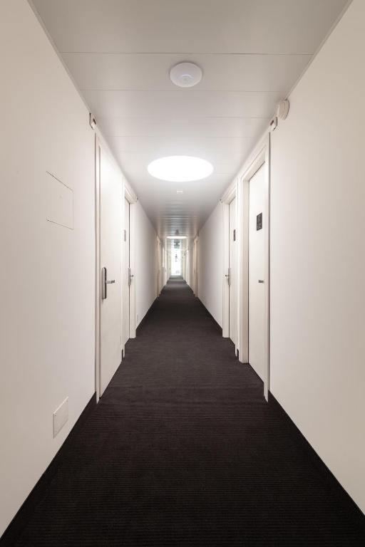 an empty corridor in an office building with white walls and a long hallway at Hotel Albergo Milano in Mendrisio