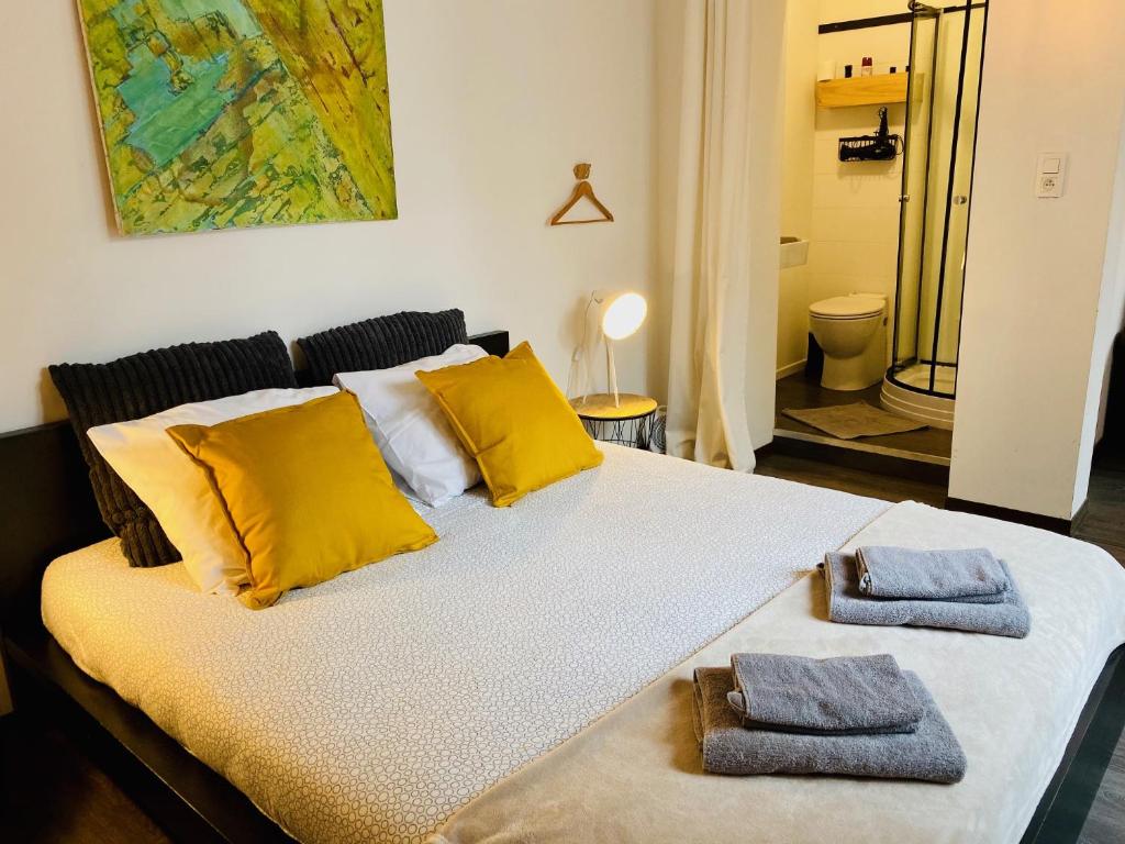 Una cama con almohadas amarillas y dos toallas. en L’atelier St Remacle, en Lieja