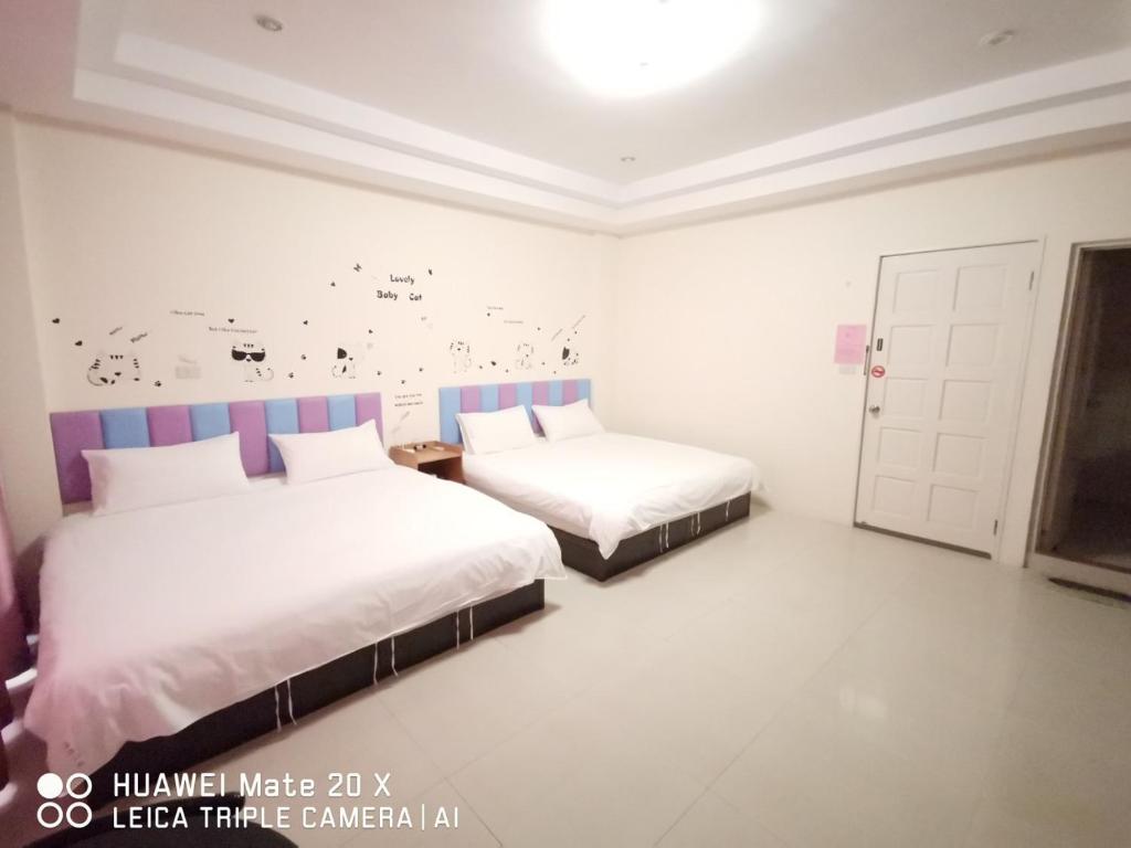 1 dormitorio con 2 camas y una pared con mariposas en 玖號民宿, en Jincheng