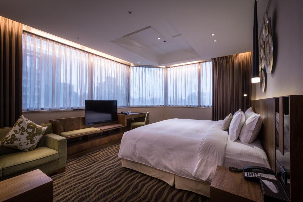a hotel room with a large bed and a television at Green World JianPei in Taipei