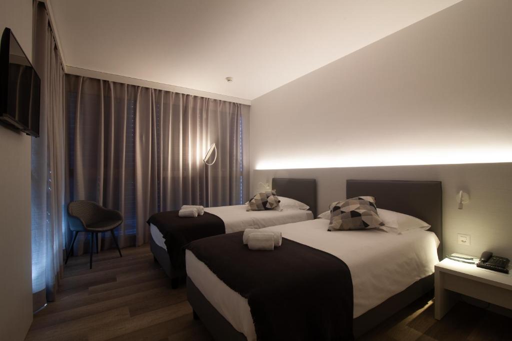a hotel room with two beds and a chair at Hotel Albergo Milano in Mendrisio