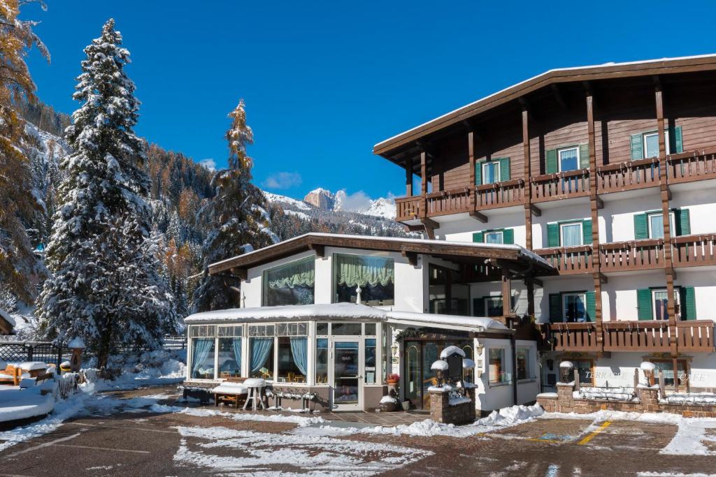 un gran edificio con nieve en el suelo en Hotel Al Lago, en Soraga