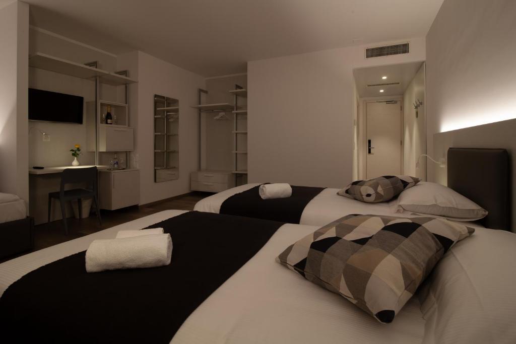 a bedroom with two beds and a kitchen in the background at Hotel Albergo Milano in Mendrisio