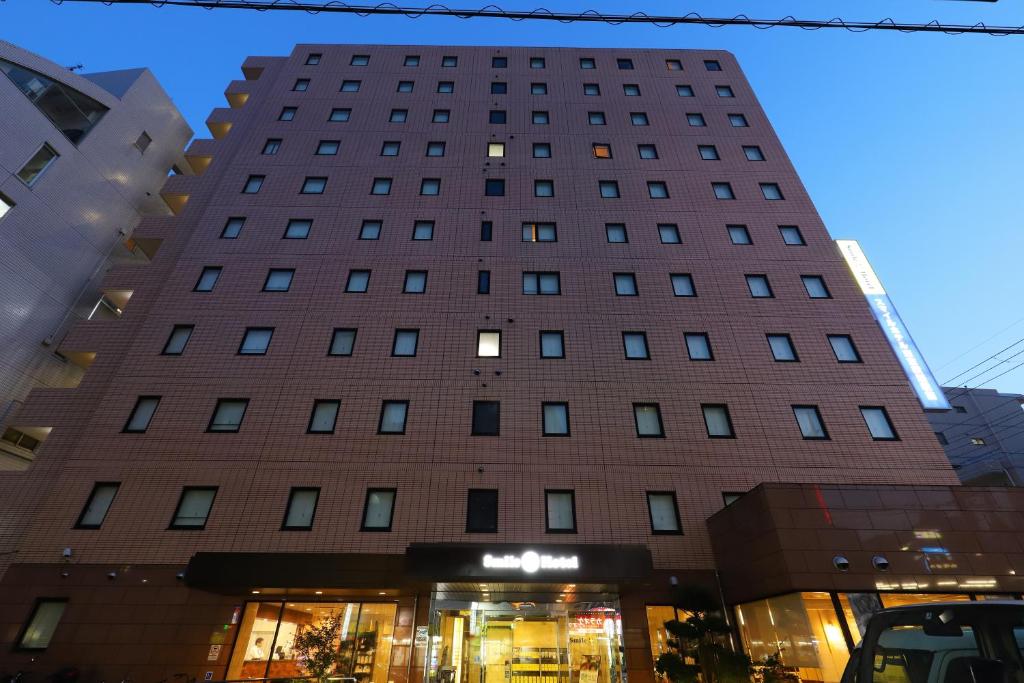 un edificio alto con una tienda delante en Smile Hotel Tokyo Ayase Ekimae en Tokio