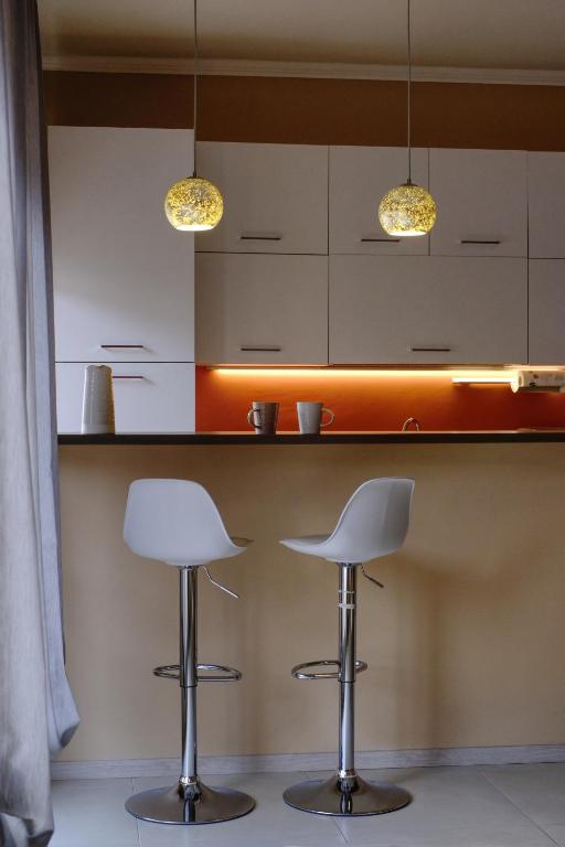 two white bar stools in a kitchen with two lights at La maison du boulevard in Aosta