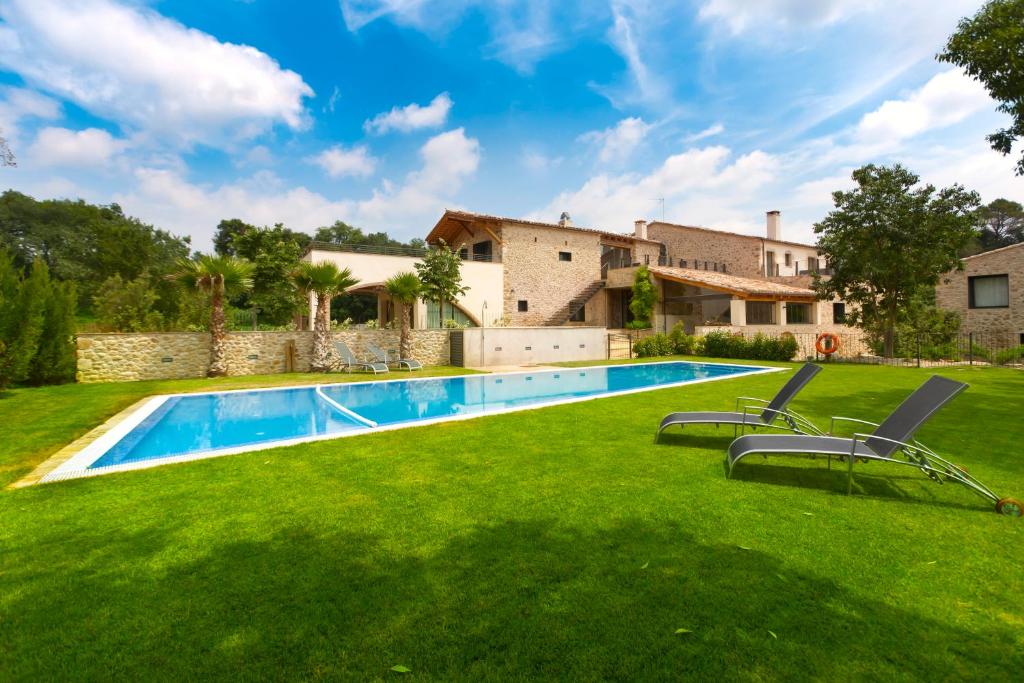 un patio con piscina y una casa en Can Clotas Hotel Masia, en Cistella