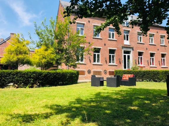 een groot bakstenen gebouw met banken voor een tuin bij L'EVEIL in La Louvière