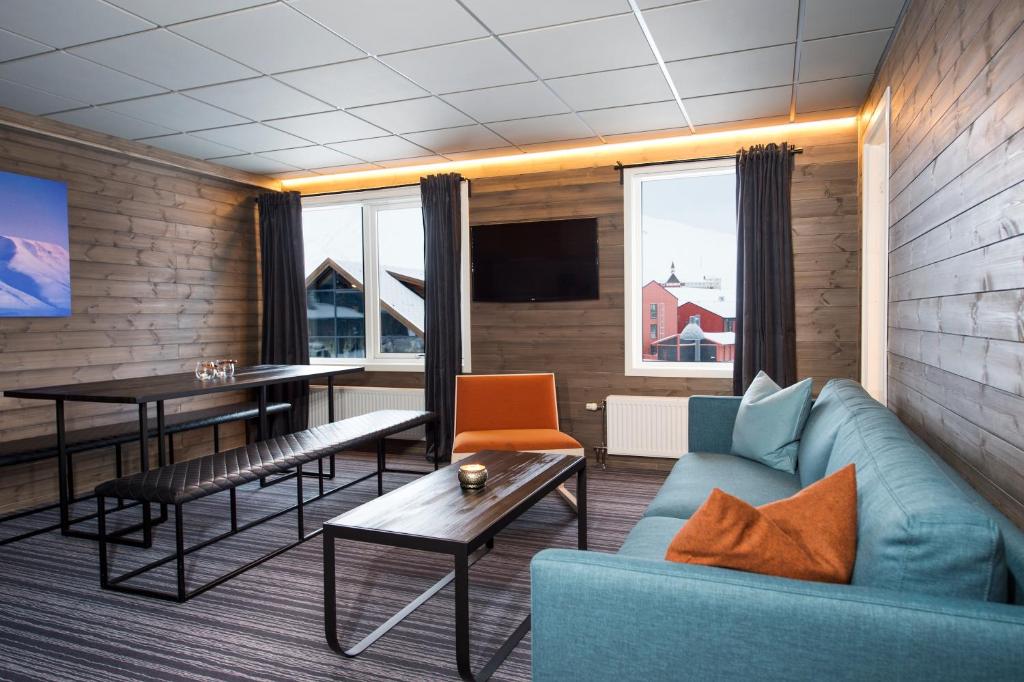Svalbard Hotell | Lodge في لونغييربين: غرفة معيشة مع أريكة وطاولة