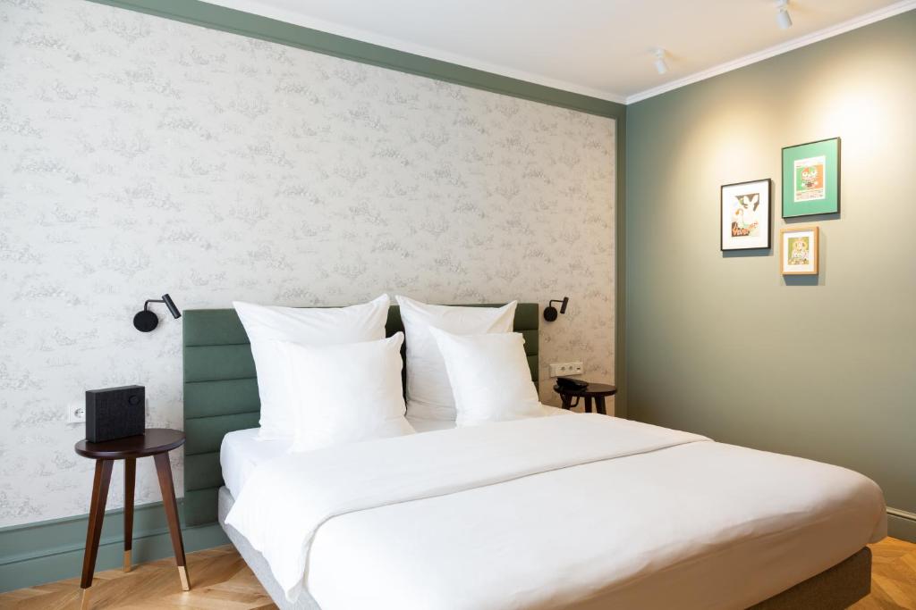 a bedroom with a large bed with white sheets at Hotel Perrin - former Carlton in Luxembourg