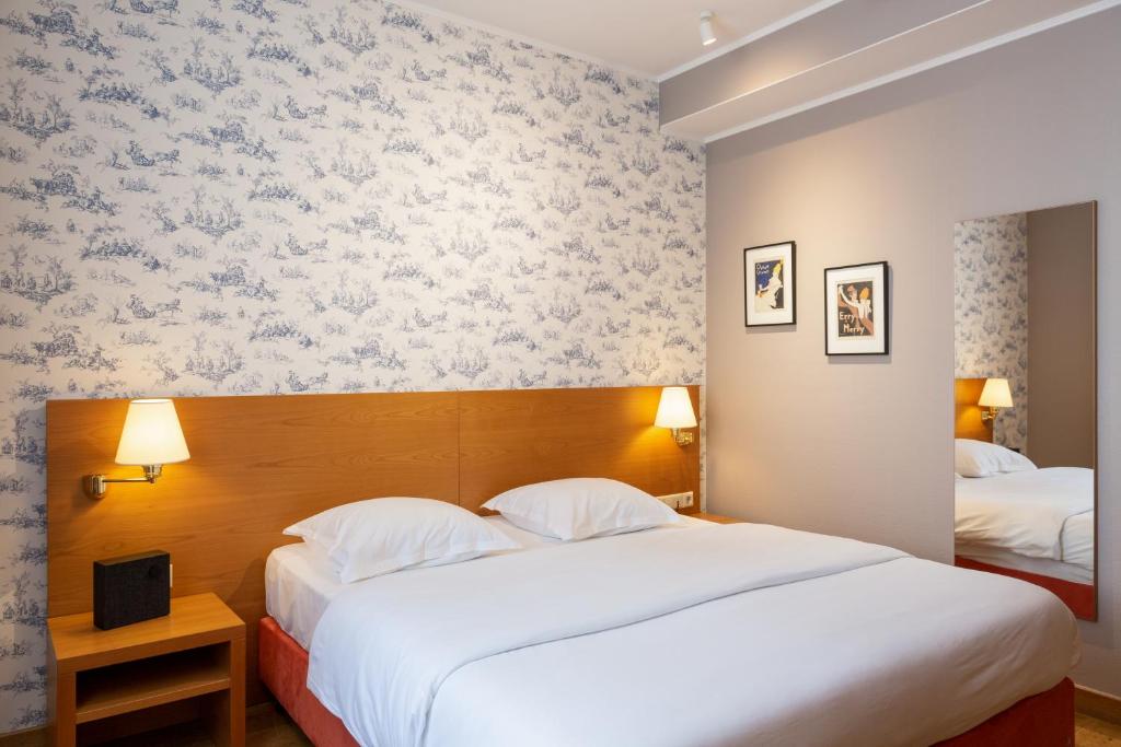 two beds in a hotel room with wallpaper at Hotel Perrin - former Carlton in Luxembourg