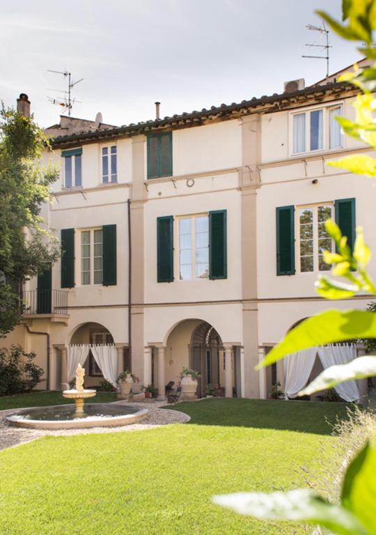 ein großes Haus mit einem Brunnen im Hof in der Unterkunft LUCUS Exclusive Bed and Breakfast in Lucca