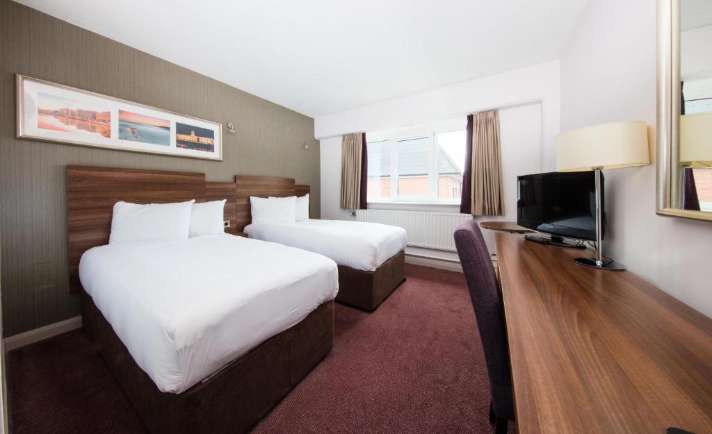 a hotel room with two beds and a flat screen tv at Leonardo Hotel Cork - Formerly Jurys Inn in Cork