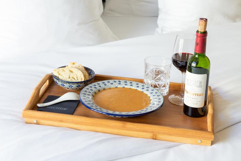 a tray with a bottle of wine and a plate of food at Hotel Perrin - former Carlton in Luxembourg