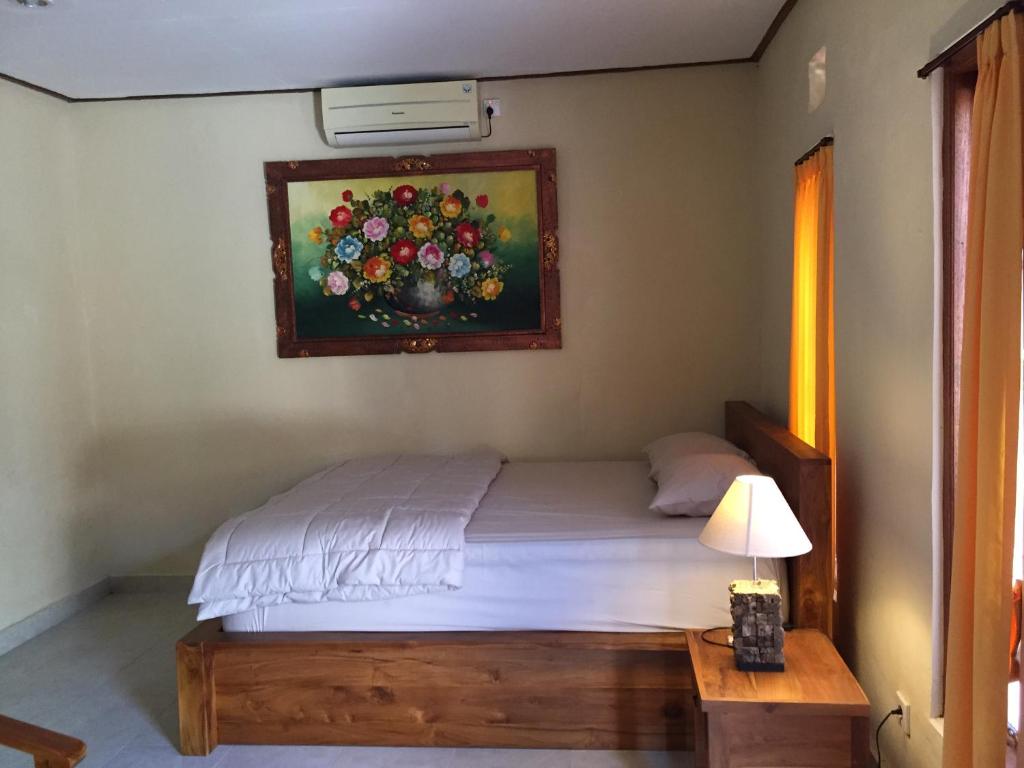 a bedroom with a bed with a painting on the wall at MALINI Homestay in Ubud