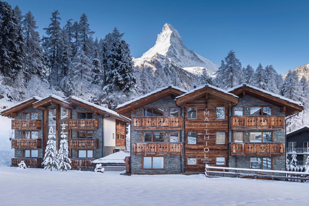 a large log building in the snow with a mountain at Matthiol Boutique Hotel in Zermatt