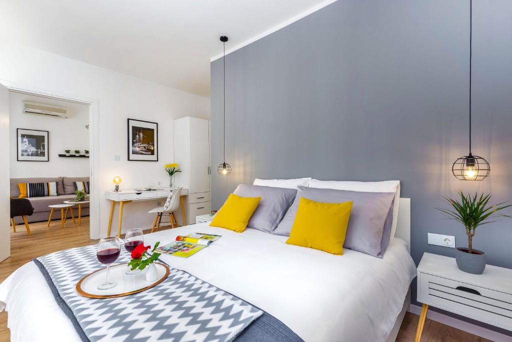 een slaapkamer met een groot wit bed met gele kussens bij Rijeka Apartments Terra I & II in Rijeka