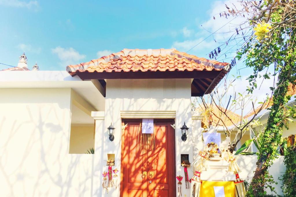 a white house with a red door at Kubu Green in Nusa Dua