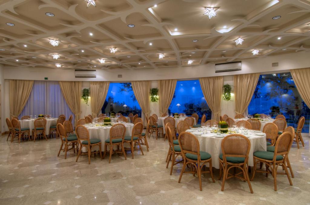 un salón de banquetes con mesas, sillas y ventanas grandes en Grand Hotel Aminta, en Sorrento