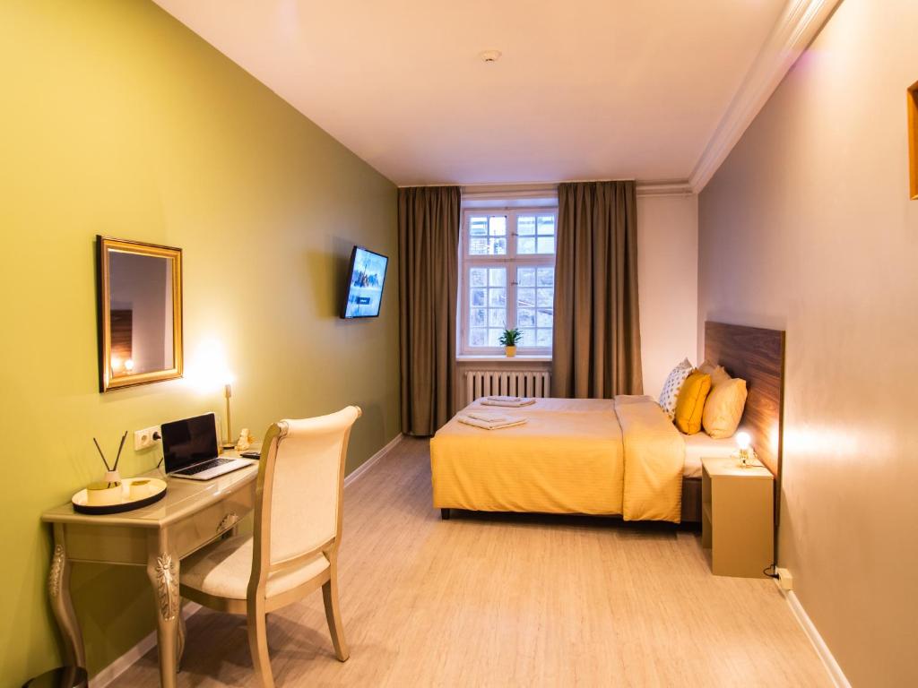 a hotel room with a bed and a desk with a computer at Allure Rooms & Coffee in Rīga