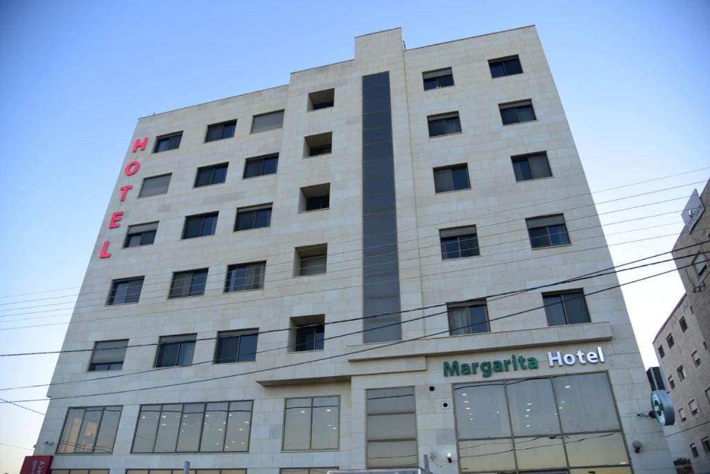 een groot wit gebouw met een bord erop bij Margarita Hotel in Amman