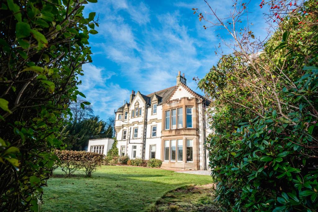 une grande maison blanche avec des fenêtres sur une pelouse dans l'établissement The Park, à Peebles