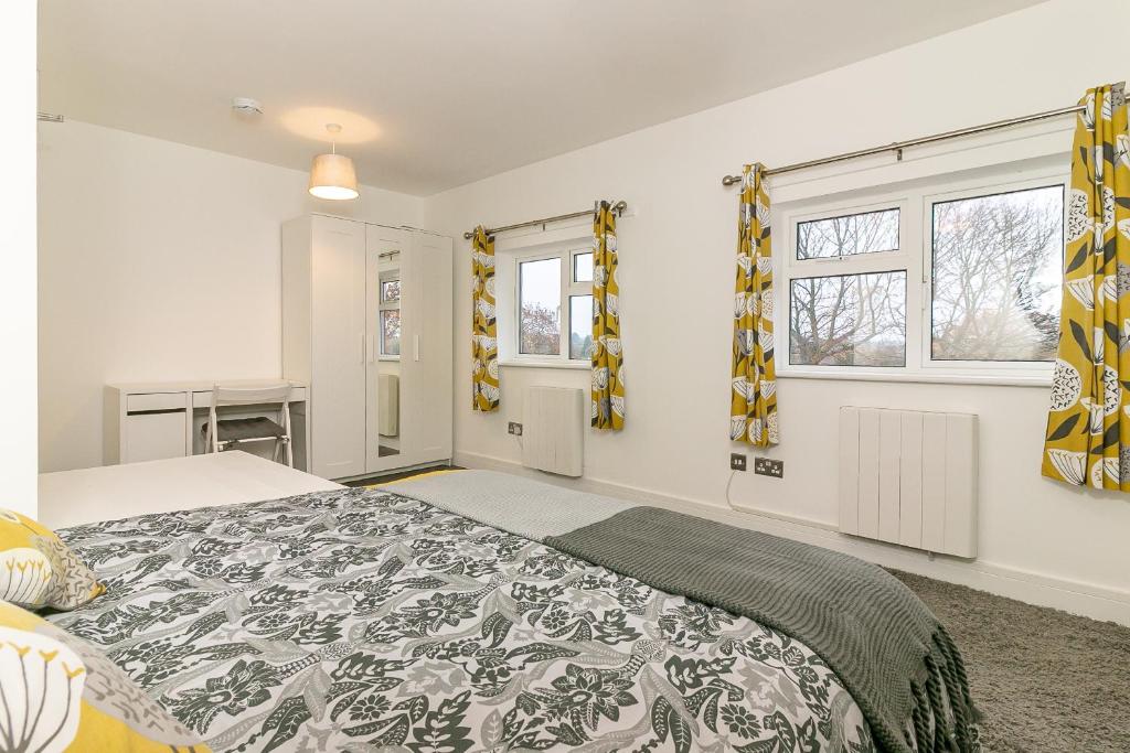 ein Schlafzimmer mit einem großen Bett und zwei Fenstern in der Unterkunft Denby Lodge in Letchworth
