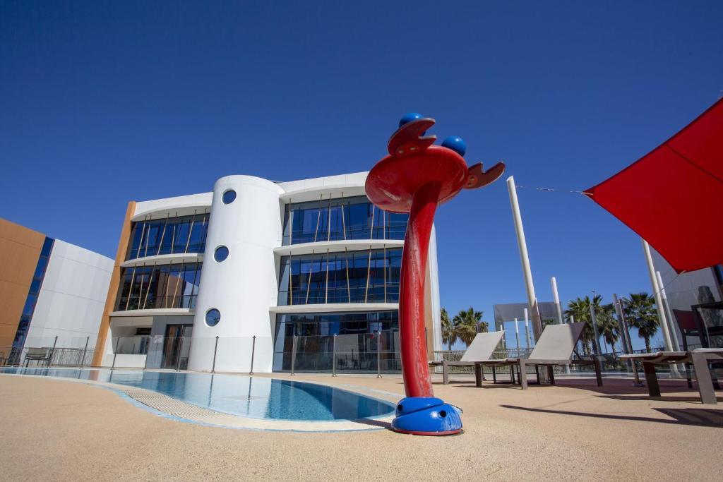 a building with a red squid statue in front of a pool at SoBlue Hôtel in Antibes