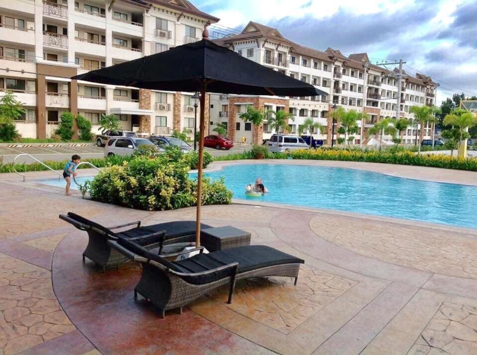 - un parasol et des chaises longues à côté de la piscine dans l'établissement Davao 2br One Oasis Beside SM Mall-Wifi, à Davao