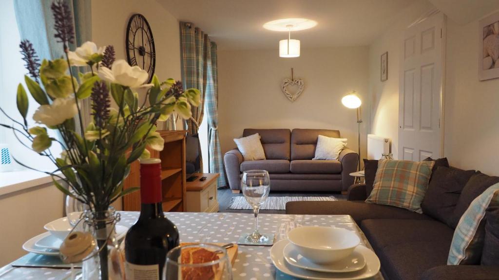 a living room with a couch and a table with a wine bottle at Hideaway Cottage in Halesworth